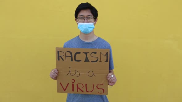 Chinese Man Wearing Protective Face Mask Holding a Poster Against Asian Racism