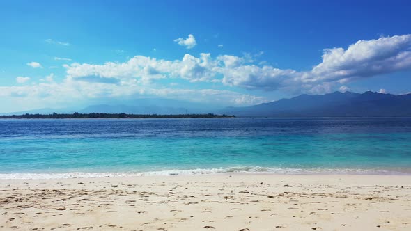 Beautiful white sand tropical beach with the turquoise emerald sea. Fluffy clouds over the mountains