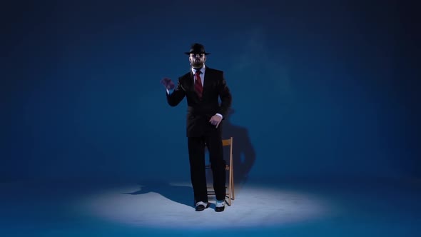 Elegant Man in a Black Hat Is Dancing an Erotic Dance. Spotlight on a Blue Background. Close Up