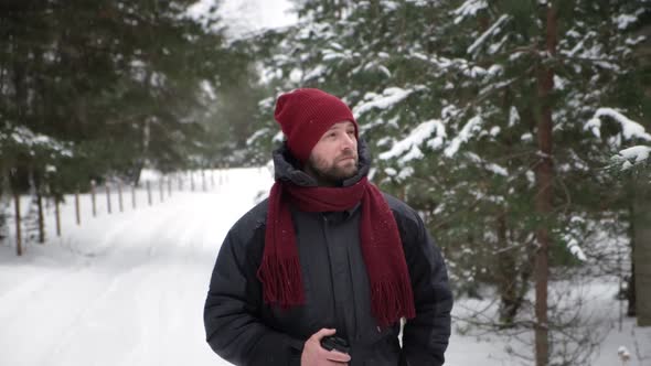 Young Man in Winter Forest Walking Drinking Hot Coffee