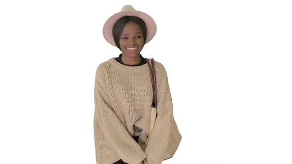 Smiling African American Woman in Knitwear and White Hat Posing While Walking on White Background