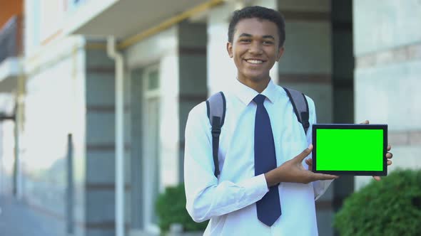 Smiling Mixed-Race High-Schooler Showing Green Screen Tablet, Educational App