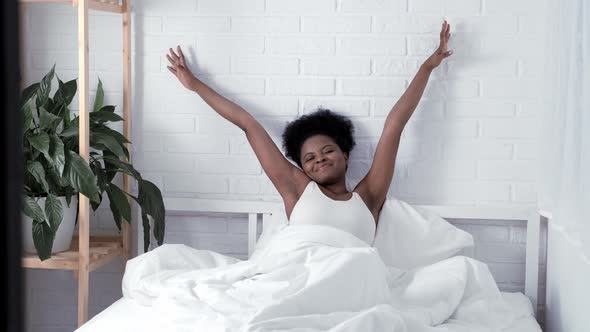 Lazy Morning Young Black Girl in Pajamas Stretching in Her Bed Napping at Home in Bedroom