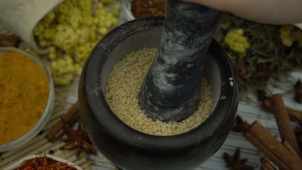 Woman's hand mixes and crushes sesame seeds by granite mortar