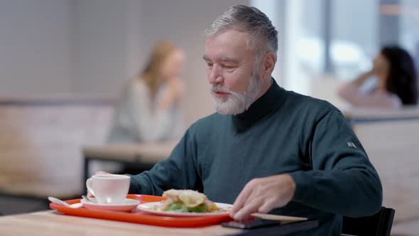 Portrait of Happy Smiling Male Retiree Dining in Cafeteria