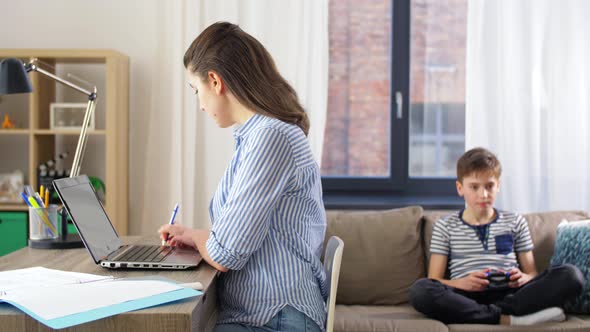 Mother Working at Home and Son Playing Video Game