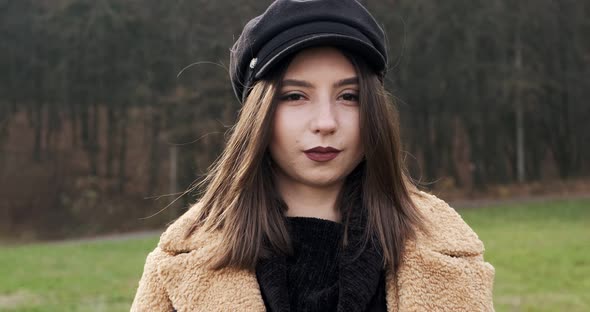 Portrait of Young Attractive Female Who Smiling and Looking at the Camera on Green Lawn. Cheerfully