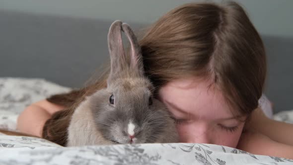 a Little Cute Girl is Playing and Hugging a Rabbit