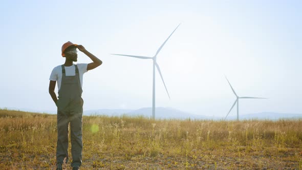 Engineer Standing on Field with Windmills