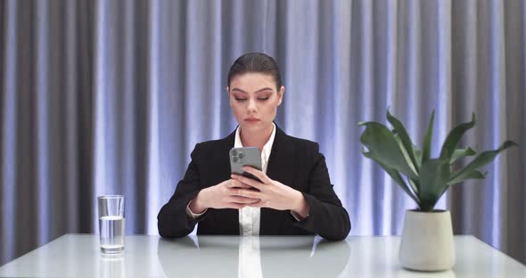 Businesswoman Sitting at the Table and Typing Text on Smartphone Communication on the Internet