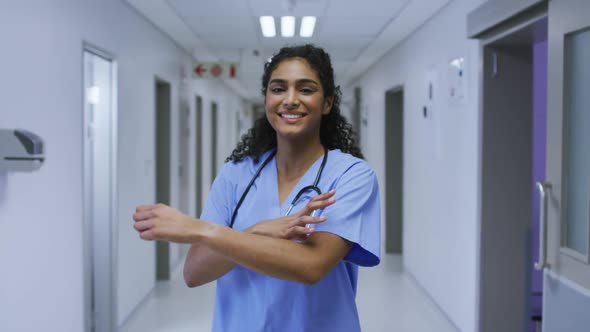 Portrait of smiling asian female doctor wearing scrubs standing in hospital corridor