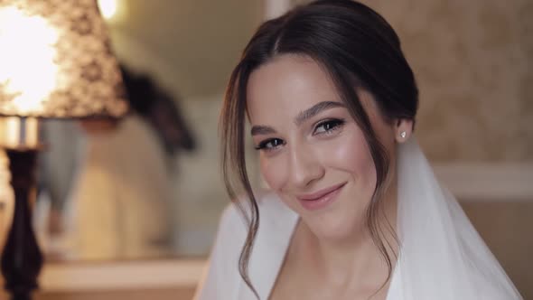 Beautiful Bride in White Boudoir Dress Looking at Camera and Smiling Wedding Morning Preparations