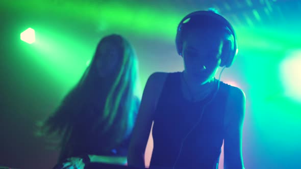 Two Beautiful Young Women DJ Play the Music on the Mixing Console in the Nightclub