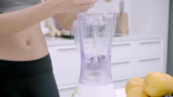 Asian woman using blender to make grape juice in the kitchen, use organic fruit lots.