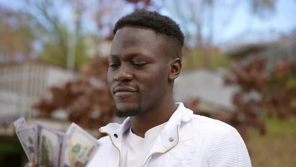 Wealthy Satisfied African American Man Admiring Cash Standing in Autumn Park Outdoors