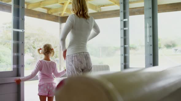 Rear view of mother and daughter standing with arms up at home 4k