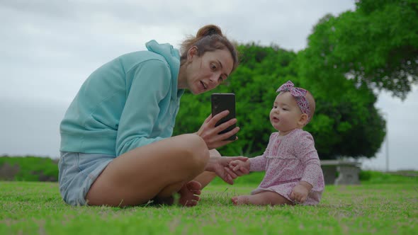 Mother Shows Baby Girl Something in Mobile Phone