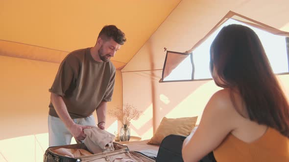 Couple Unpacking Suitcases on Bed