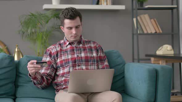 Man Making Online Payment on Laptop on Sofa