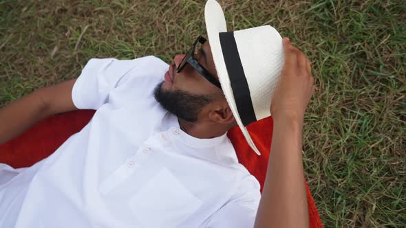 Top View Portrait of Handsome Relaxed African American Young Man Lying on Green Lawn with Hands