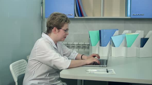 Female Doctor in Glasses Using Her Laptop Computer at Clinic