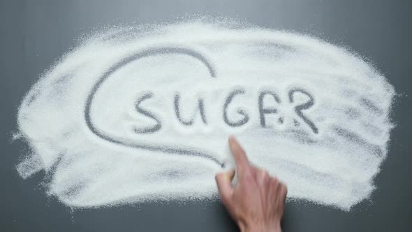 Male hand draws heart with finger around word sugar.