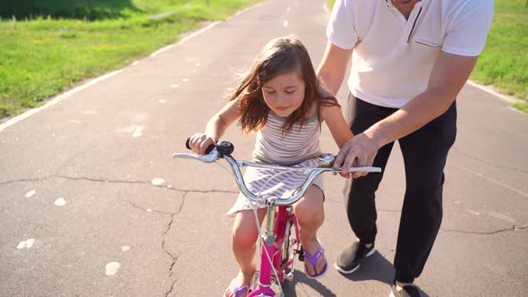 Happy Father Rejoices That Her Daughter Learned to Ride a Bike