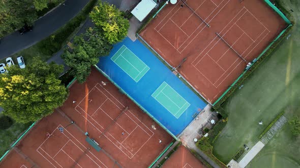 Aerial top down rising above clay tennis courts and a professional golf course on a sport club at su