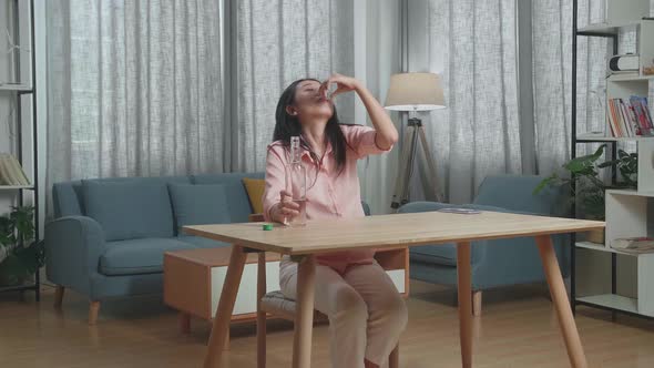 Drunk Asian Woman Pouring Vodka In A Shot Glass And Cheer To Camera Before Drinking At Home