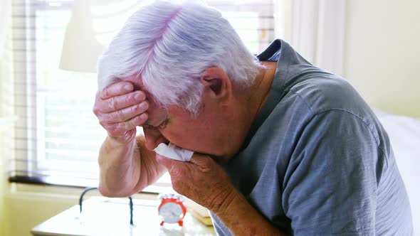 Sick senior man coughing in bedroom