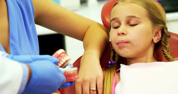 Dentist showing young patient how to brush teeth