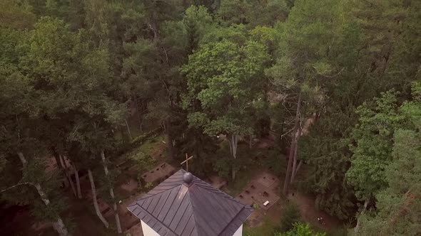 Aerial view of a traditional Chapel surrounded by a cemetery and a forest in Estonia.