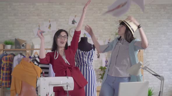 Two Positive Fashionable Young Fashion Designers Throw Papers for Joy Slow Mo