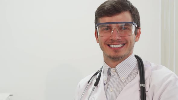 A Smiling Doctor Puts on Special Transparent Laboratory Glasses