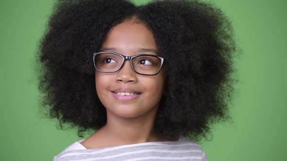 Young Happy African Girl with Afro Hair Smiling and Thinking Against Green Background