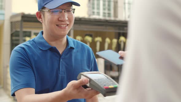 Young postal delivery courier man holding parcel boxes for sending to customer.