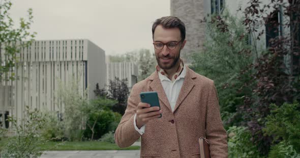 Crop View of Bearded Man in Stylish Outfit Using Smartphone and Smiling