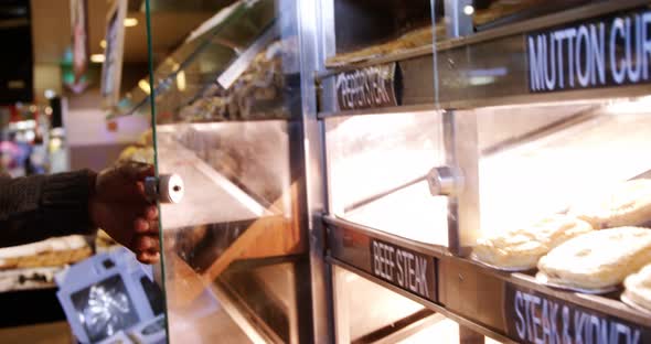 Man selecting cooked mutton and chicken steak in display