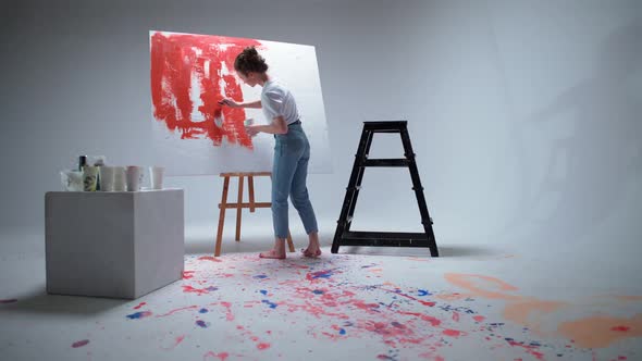 Back View Female Artist Draws with a Brush on a Large Canvas in a White Room a Talented Artist Draws