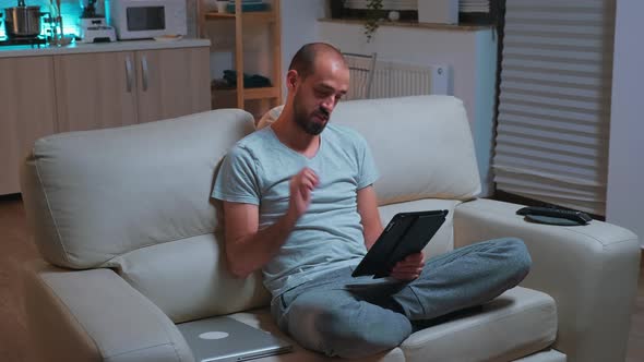 Focused Man with Beard Sitting on Couch in Front of Television