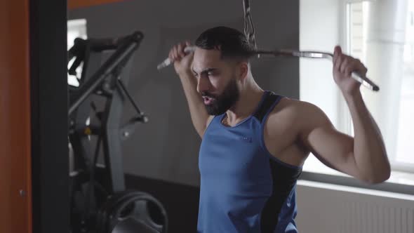 Young Confident Sportsman Training Muscles Using Pull Down Machine. Concentrated Middle Eastern Man