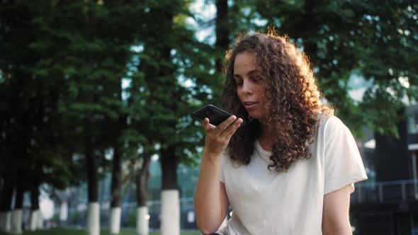 Young Mixed Race Young Woman Holding a Mobile Phone and Recording a Voice Message