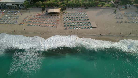 Beach Top View of Waves Crashing Against the Beach with People and Umbrellas on the Shore on a