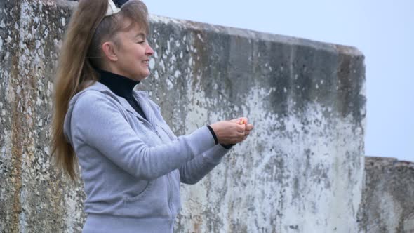 Mature Woman Is Feeding Gulls On The Shore Of The Sea 8