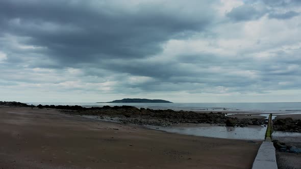 Aerial low view of drone rising over  beach landscape and revealing the Irish sea