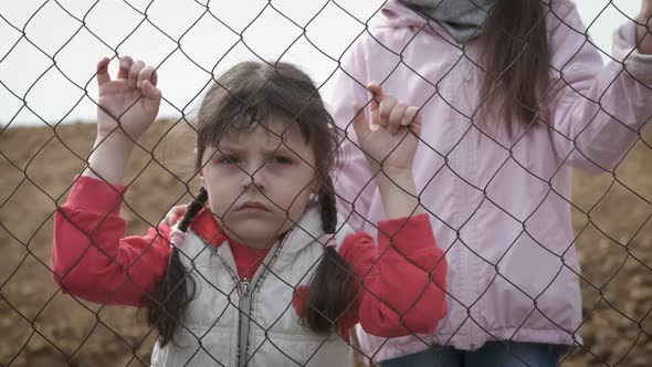 Sad childhood. Children behind the iron grid. 