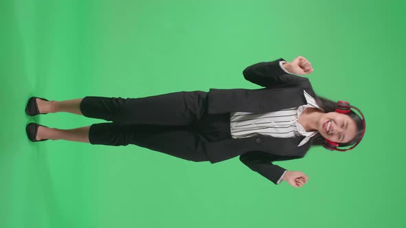 Full Body Of Asian Business Woman Listening To Music With Headphones And Dancing In The Green Screen