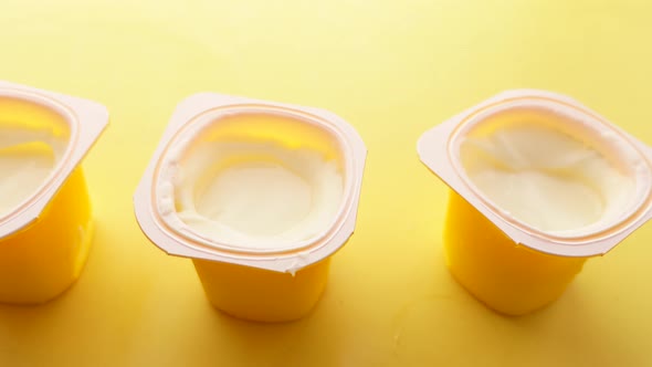 Fresh Yogurt in a Plastic Container and Spoon on Table