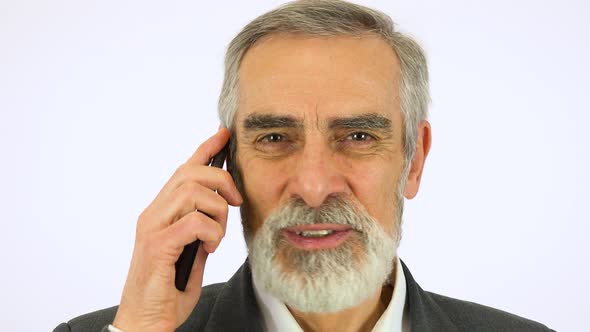 An Elderly Man Talks on a Smartphone and Looks at the Camera - Face Closeup - White Screen Studio