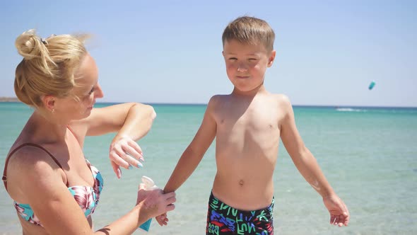 Portrait of a Mother Taking Care of Her Son, a Woman Applying Sunscreen Lotion To the Baby's Skin